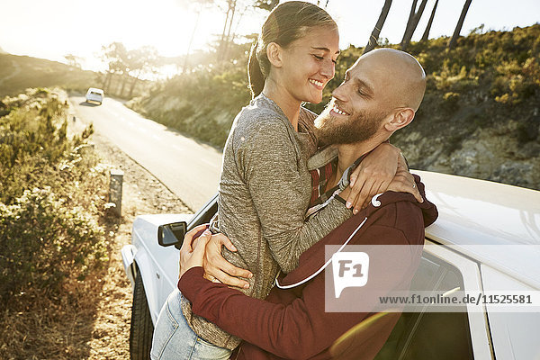 Happy couple in love leaning against car