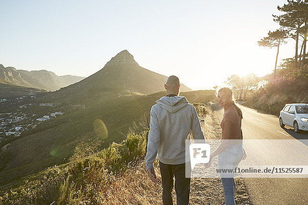 Südafrika  Kapstadt  junges Paar  das Hand in Hand am Straßenrand läuft