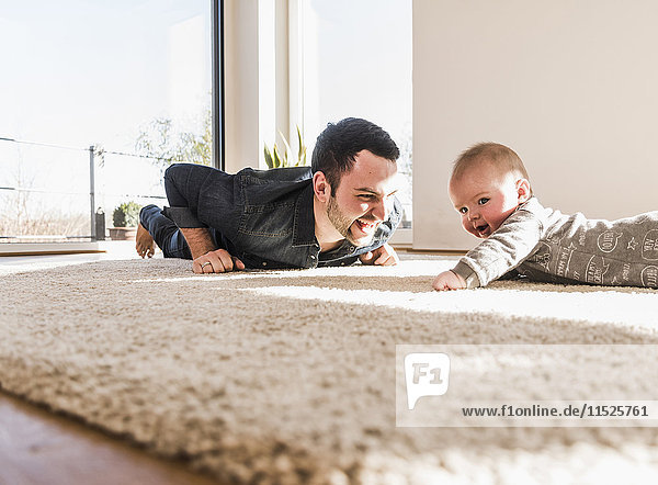 Father and baby son playing crawling on carpet