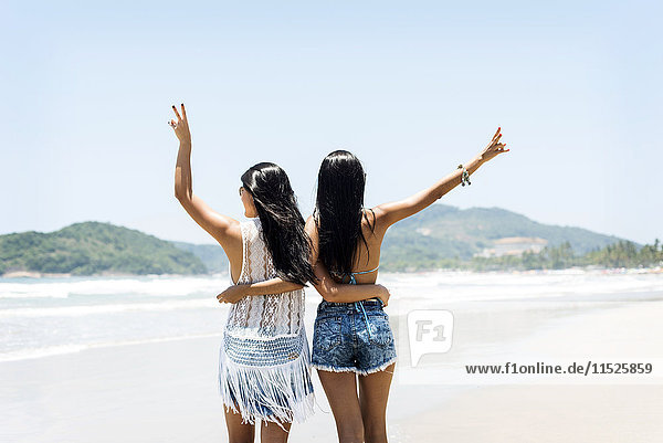 Brasil  Sao Paulo  Ubatuba  two young women standing arm in arm on the beach
