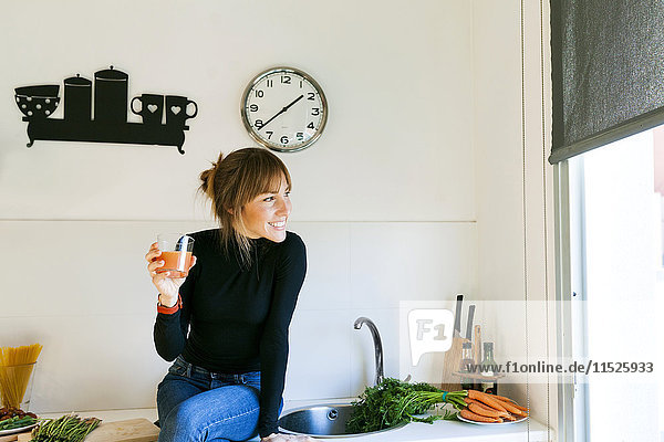 Junge Frau trinkt frischen Grapefruitsaft in ihrer Küche