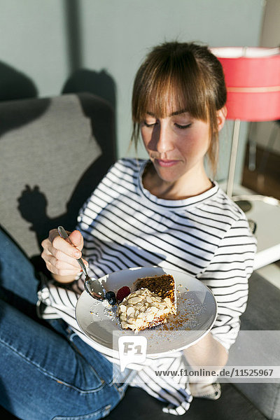 Junge Frau isst ein Stück veganen Kuchen.