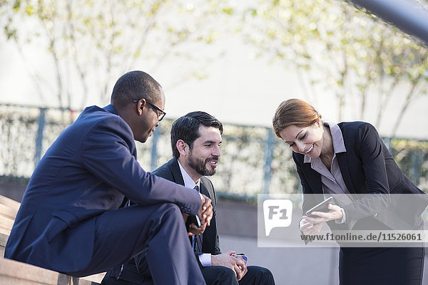 Businesspeople sharing tablet outdoors