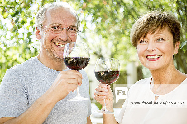 Happy senior couple having glass of red wine outdoors