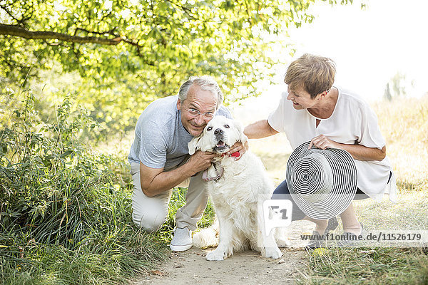 Senior couple petting dog outdoors