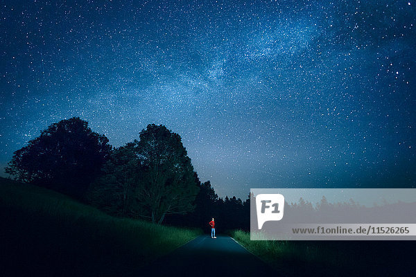 Österreich  Mondsee  junger Mann steht auf leerer Straße unter Sternenhimmel