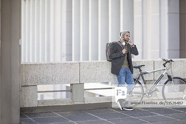 Junger Mann auf dem Handy neben dem Fahrrad