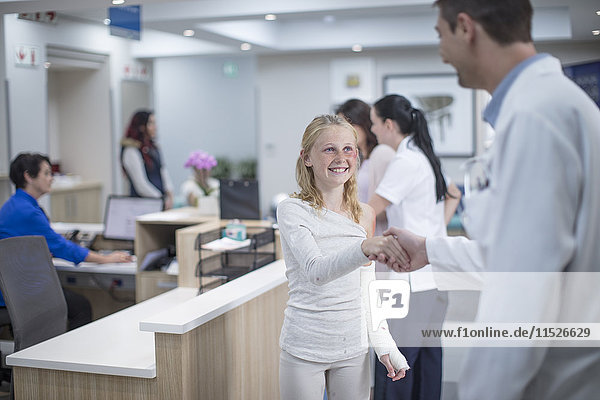 Krankes Mädchen begrüßt Arzt an der Rezeption im Krankenhaus