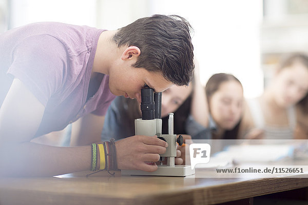 Wissenschaftsstudent im Unterricht mit Blick durchs Mikroskop