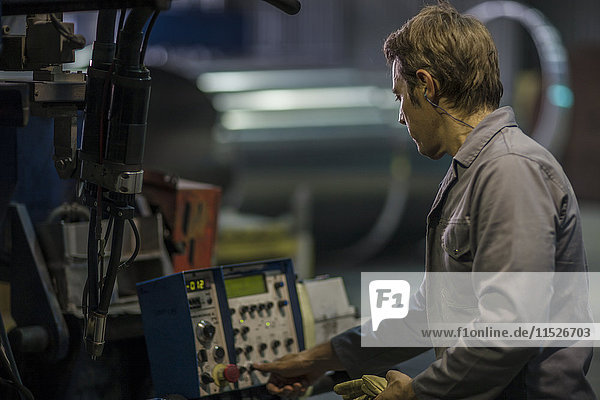 Worker operating machinery at control panel in factory
