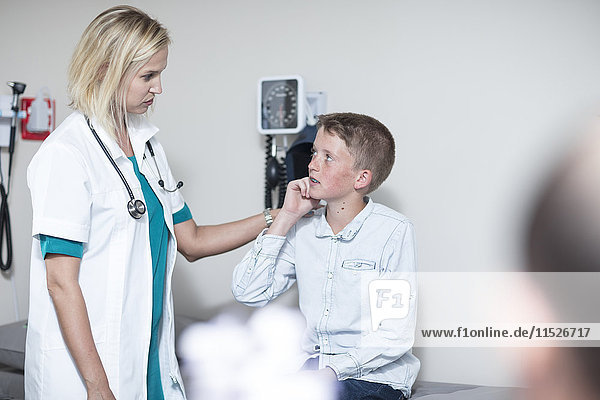 Kinderärztin untersucht Junge mit Otoskop
