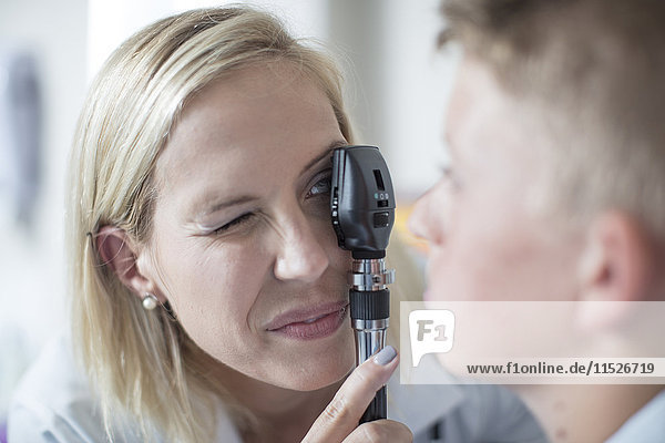 Female pedeatrician examining boy with an otoscope