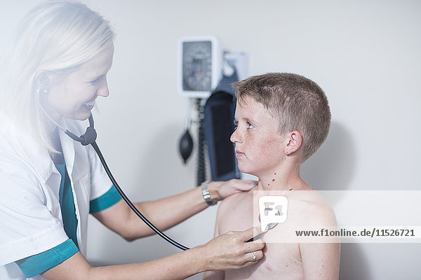 Kinderärztin untersucht mit Stethoskop die Lunge eines Jungen