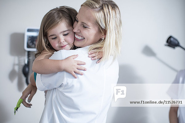Kinderarzt umarmt ein kleines Mädchen