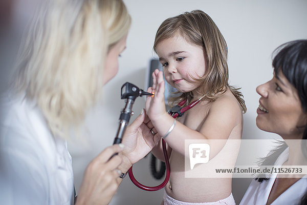 Kleines Mädchen beim Kinderarzt beim Spielen mit dem Otoskop