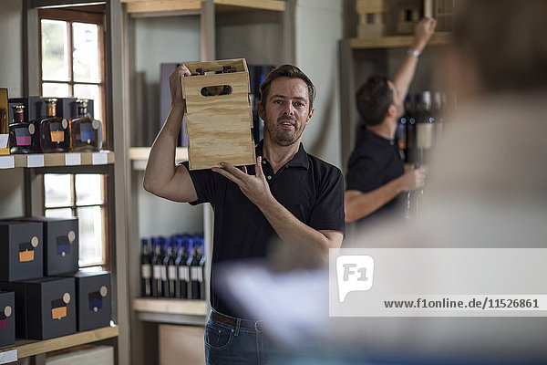 Man carrying crate of wine in shop
