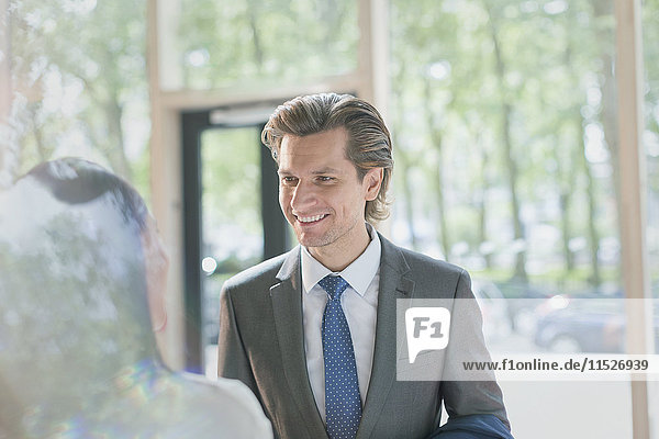 Smiling businessman talking to businesswoman in lobby