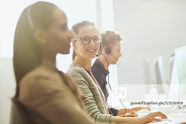 Portrait smiling female telemarketer wearing headset at computer in office