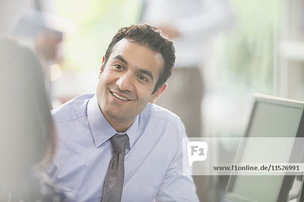 Attentive  smiling businessman listening to colleague in meeting