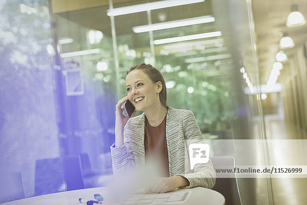 Smiling businesswoman talking on cell phone in conference room