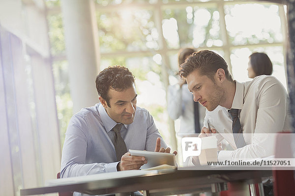 Businessmen using digital tablet at office table