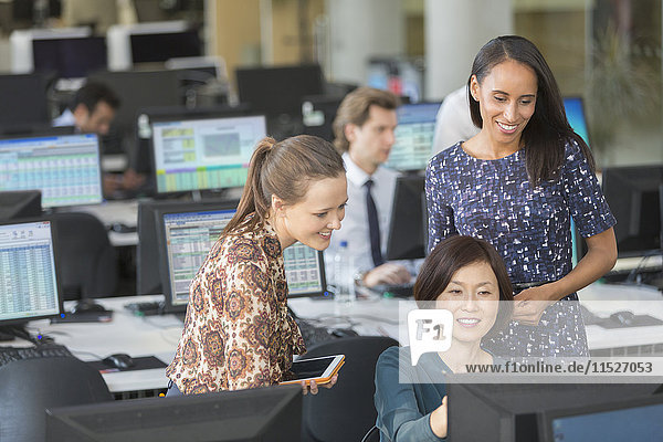 Businesswomen using computer in open plan office