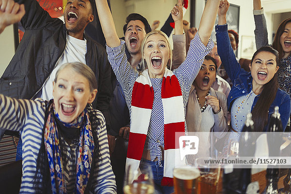 Enthusiastic sports fans cheering watching game in bar