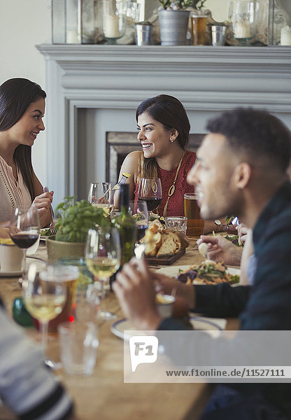Lächelnde Frauenfreunde beim Reden und Essen am Restauranttisch