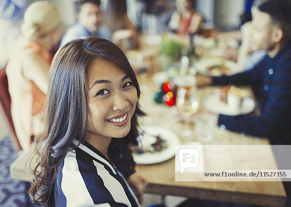 Portrait smiling woman dining with friends at restaurant table