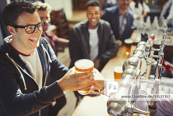 Smiling man receiving beer from bartender at bar
