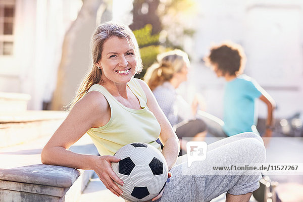 Portrait smiling woman holding soccer ball in sunny park