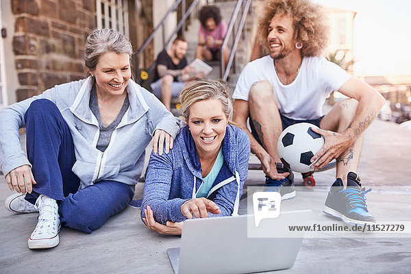 Friends with soccer ball hanging out using laptop