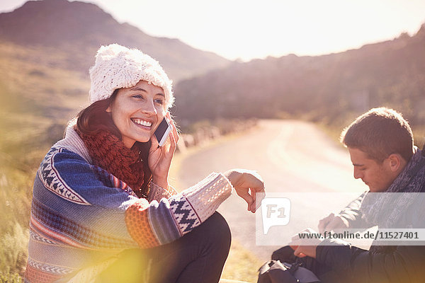 Smiling young woman talking on cell phone at sunny  remote roadside