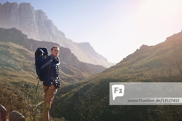 Junger Mann mit Rucksackwanderung  Blick auf den sonnigen Bergblick