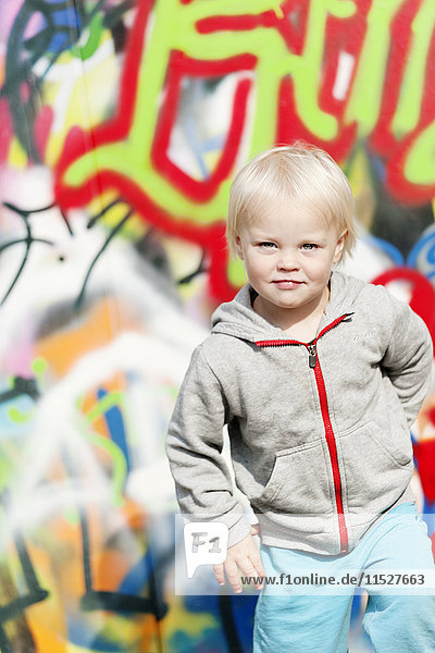 Porträt eines blonden Jungen vor einer mit Graffiti beschmierten Wand