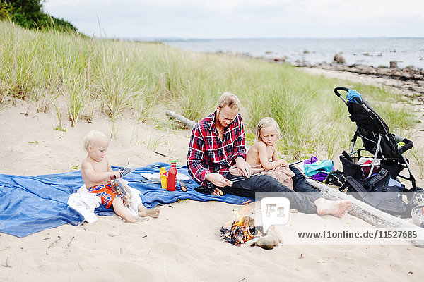 Vater mit zwei Kindern entspannt am Strand