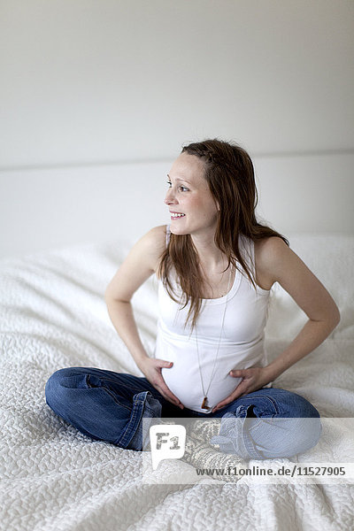 Smiling pregnant woman on bed