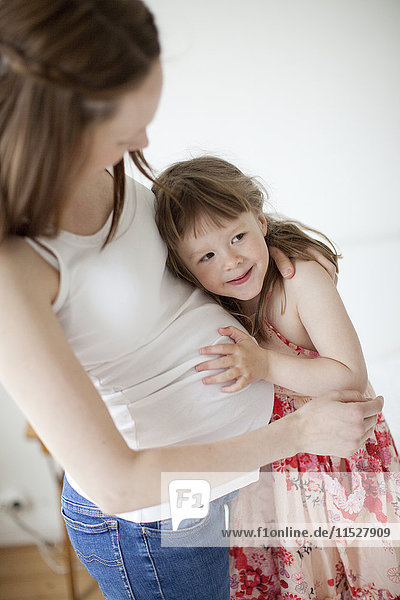 Mädchen umarmt Mütter schwangeren Bauch