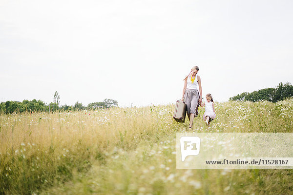 Mother with daughter walking in meadow