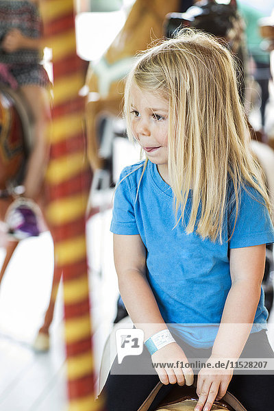 Small girl riding carousel