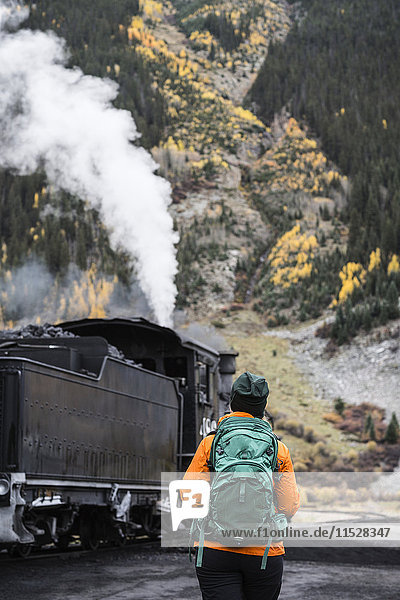 Tourist  der in den Bergen spazieren geht und eine Dampflokomotive betrachtet