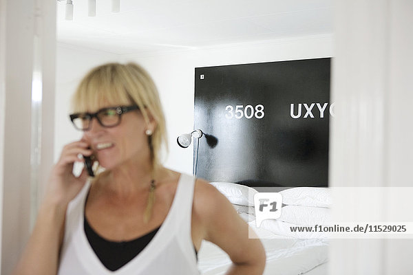 Mature woman in bedroom talking via cell phone
