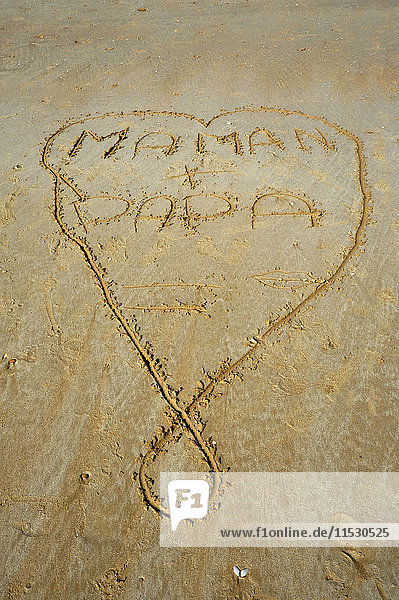 Frankreich  Vendee  Saint-Jean-de-Monts  Zeichnung einer Herzform auf dem Sand  in der Mama und Papa geschrieben sind.