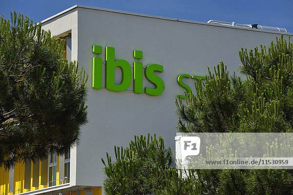 Frankreich  Detail des Ibis Hotels in der Stadt Reze. Zeitgenössische Architektur und bunt unter Bäumen. Blauer Himmel