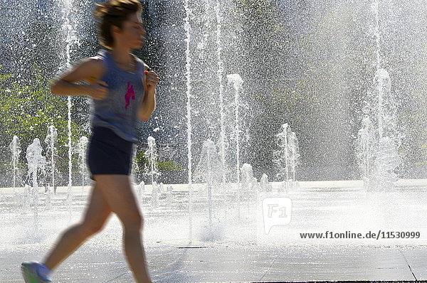 France Paris 15th district Parc Andre Citroen. Woman running in front of the water jets