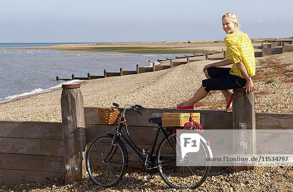 Woman Sitting on Fence at Beach