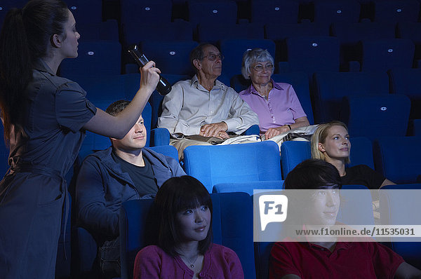 Platzanweiser leuchtet auf leeren Sitz im Kino