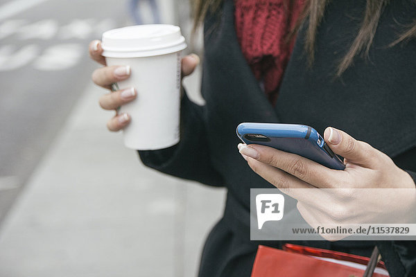 Spanien  junge Frau mit Smartphone und Kaffee zum Mitnehmen  Nahaufnahme