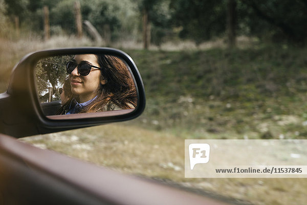 Spiegelung der jungen Frau im Außenspiegel eines Cabriolets