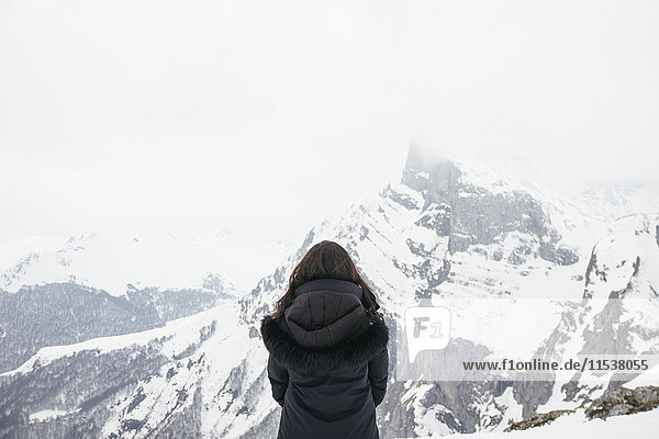 Frau vor einem verschneiten Berg in Picos de Europa